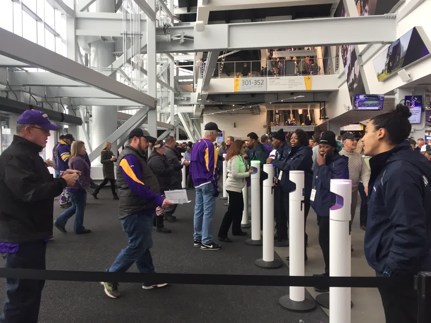 Guests move through service and screening stations inside a large venue.